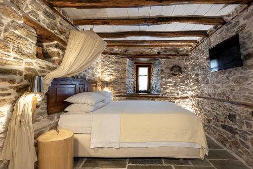 a bedroom with a bed in a stone wall at Mountain's Secret in Mouresi