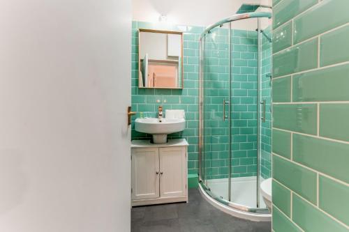 a bathroom with green tiles and a sink and a shower at Pass the Keys Sunny Kennington terrace Apartment in London