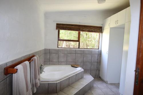 a bathroom with a bath tub and a window at Tsitsikamma on Sea Self-catering Cottages in Witelsbos