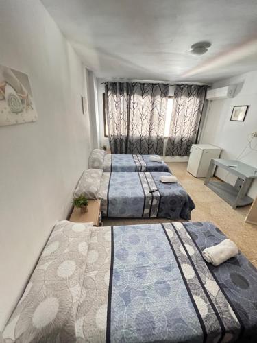 3 camas sentadas en una habitación con ventana en pensión La Parada en Alicante