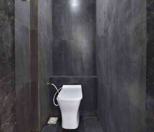 a bathroom with a white toilet in a gray wall at Hotel Infini Palace City Center in Surat