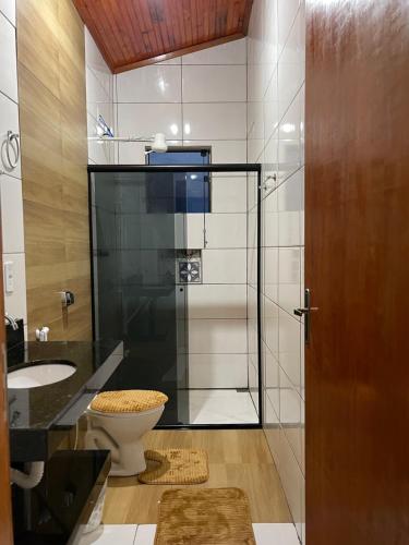 a bathroom with a toilet and a glass shower at Casa Por do Sol. in São Thomé das Letras