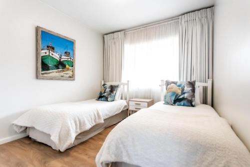 two beds in a white room with a window at Bayview 208 in Hermanus