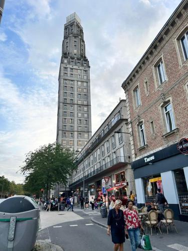 two people walking down a street with a tall building at Appt 1 à deux pas de la gare d'Amiens in Amiens
