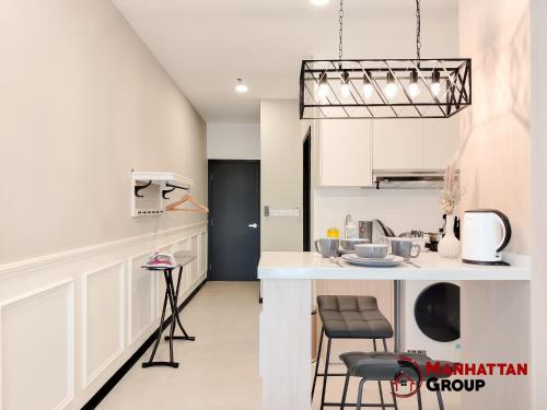 eine Küche mit weißen Schränken und einer Theke mit Stühlen in der Unterkunft Neu Suites By Manhattan Group in Kuala Lumpur