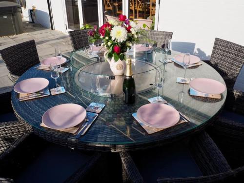 a glass table with pink napkins and a bottle of wine at The Sails in East Wittering