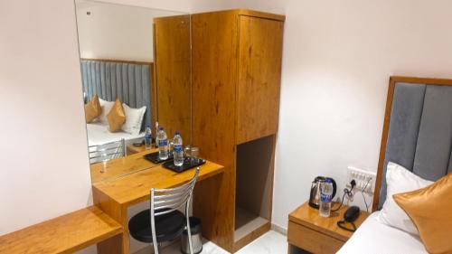 ムンバイにあるHotel Palms Residency, Chembur Mumbaiのデスク、ベッド、鏡が備わる客室です。