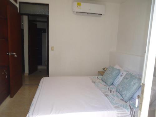 - un lit blanc avec des oreillers bleus dans une chambre dans l'établissement APARTA-ESTUDIO LA TOMA, à Neiva