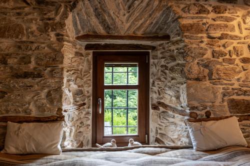 a bedroom with a window in a stone wall at Mountain's Secret in Mouresi