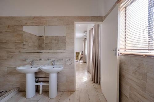 a bathroom with two sinks and a mirror at Lovely deluxe with outdoor pool and gym - 2145 in Victoria Falls