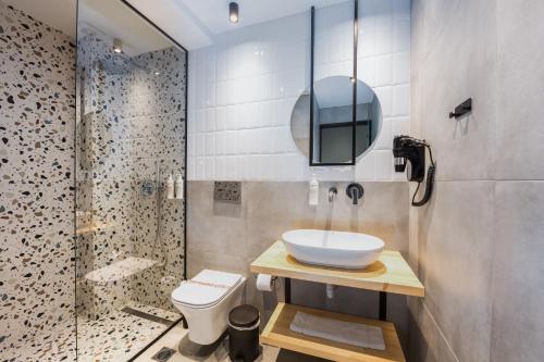 a bathroom with a sink and a shower and a toilet at Centro Hotel Ioannina in Ioannina