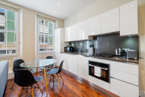 a kitchen with white cabinets and a table and chairs at Superb One Bedroom Apartment in Soho in London