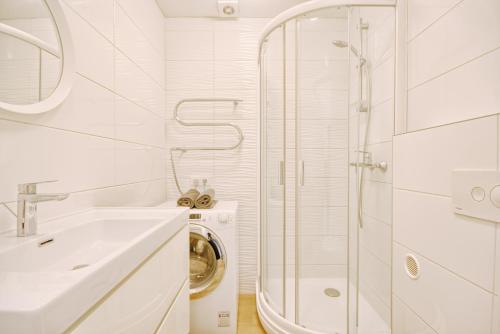 een witte badkamer met een wastafel en een douche bij DaGys apartments in Druskininkai