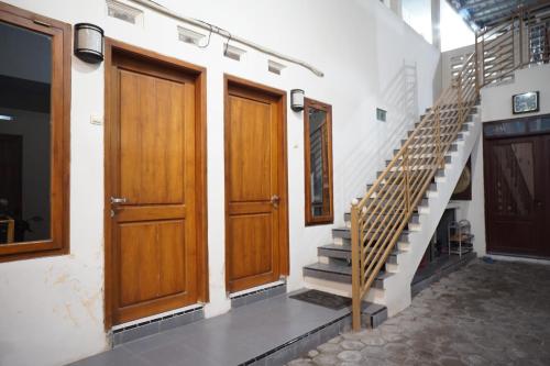 korytarz z dwoma drewnianymi drzwiami i schodami w obiekcie OYO Life 93038 Kost Putra Malilah w mieście Lumajang