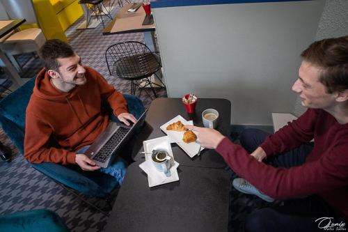 two men sitting at a table with a laptop at ibis Limoges Centre in Limoges