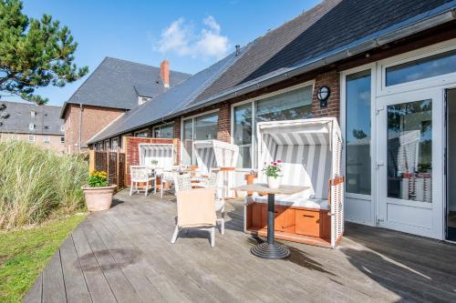 a patio with white chairs and a table on it at Steger-Hüs Wohnung 38 in Rantum