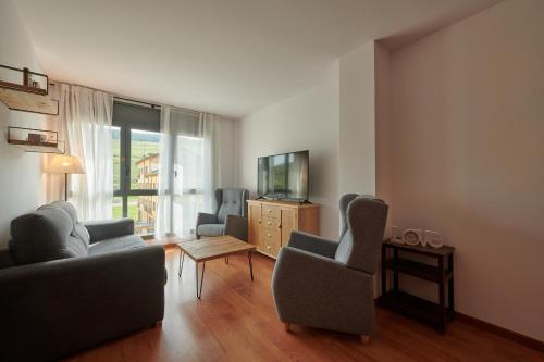 a living room with chairs and a tv and a table at Hauzify I Apartament Bella Molina in Alp