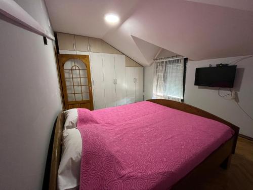 a bedroom with a bed with a pink blanket at Apartman D&D in Vukovar