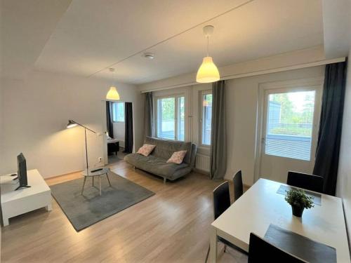a living room with a couch and a table at Kotimaailma - Tilava kaunis kaksio Myyrmäessä Vantaalla in Vantaa
