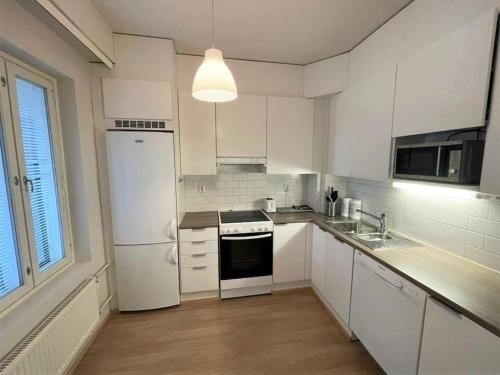 a kitchen with white cabinets and a white refrigerator at Kotimaailma - Tilava kaunis kaksio Myyrmäessä Vantaalla in Vantaa