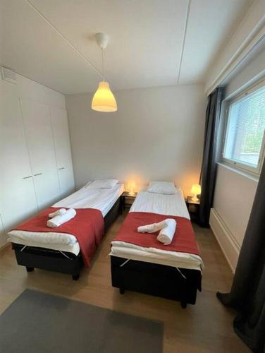 two twin beds in a room with a window at Kotimaailma - Tilava kaunis kaksio Myyrmäessä Vantaalla in Vantaa