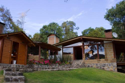 a house with a porch and green grass at Cabañas El Estribo Hotel in Valle de Bravo
