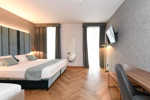 a hotel room with two beds and a desk and a television at Palazzo Santo Spirito in Bergamo