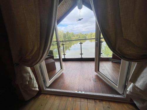 an open door to a balcony with a view of a lake at Woodpecker Log Cabin with hot tub, pizza oven bbq entertainment area, lakeside with private fishing peg situated at Tattershall Lakes in Tattershall