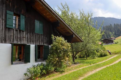 a house with green shuttered windows and a tree at Chalet Le Monteiller in Les Moulins