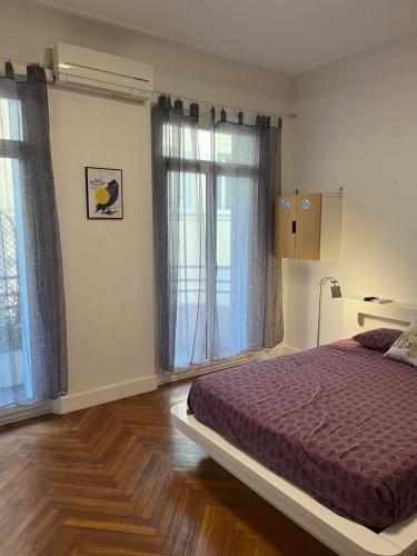 a bedroom with a bed and two large windows at Coeur de Marseille in Marseille
