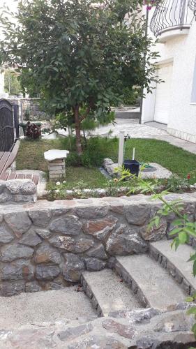 a stone retaining wall with a tree in a yard at Apartman "Kruna" in Belgrade