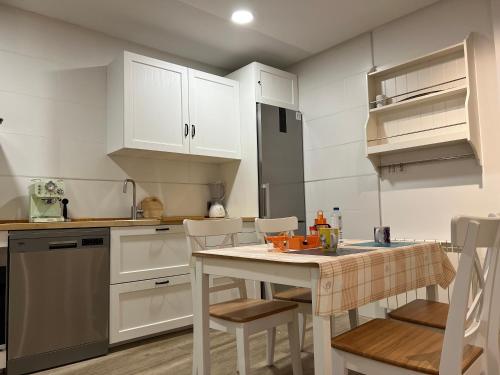 a kitchen with white cabinets and a table and chairs at Bermudo III Plaza Mayor de León in León