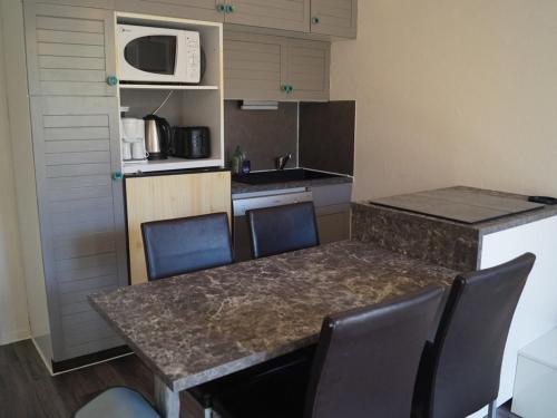 une cuisine avec une table et des chaises et un micro-ondes dans l'établissement Studio Rénové avec Terrasse sur les Pistes - Super Sauze, Enchastrayes - FR-1-165A-22, à Enchastrayes