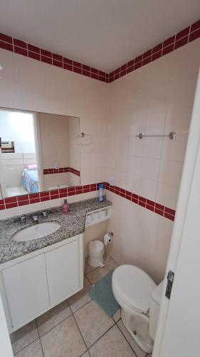 y baño con aseo, lavabo y espejo. en Apartamento de 1 quarto de frente a praia dos Ingleses, en Florianópolis