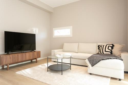 a living room with a white couch and a tv at Arctic Circle Holiday homes II in Rovaniemi