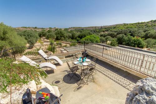 un patio con tavolo e sedie sul balcone. di Pleasant stone house & jacuzzi St Martin - Happy Rentals a Mġarr