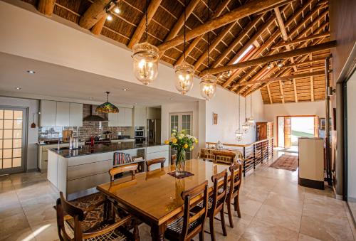 a kitchen and dining room with a wooden table and chairs at Walter’s Place in Jongensfontein