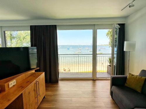 a living room with a television and a view of the ocean at Seespitz Gästehaus in Herrsching am Ammersee