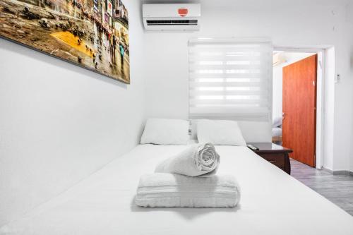 a white bedroom with a white bed and a painting at relaxing duplex in ashdod by torohome in Ashdod