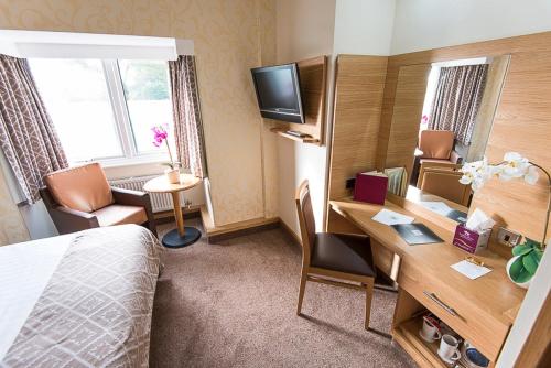 a hotel room with a bed and a desk with a computer at Fairlawns, Hotel And Spa in Walsall