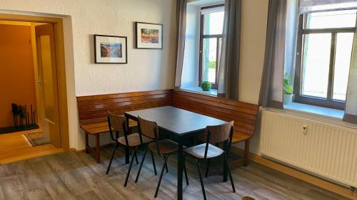 ein Esszimmer mit einem Tisch und Stühlen sowie 2 Fenstern in der Unterkunft Ferienwohnung Ida Pfeiffer in Eibenstock