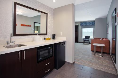 a kitchen with a sink and a mirror and a living room at Hampton Inn & Suites Columbia/Southeast-Fort Jackson in Columbia