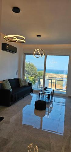 a living room with a black couch and a glass table at Infinity sea view in Lavrio