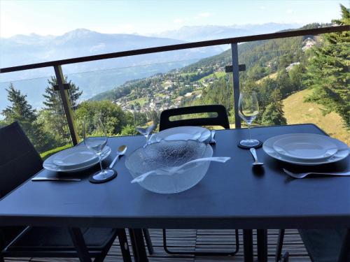 a blue table with plates and glasses on a table with a view at Apartment Clair-Azur B 65 by Interhome in Randogne
