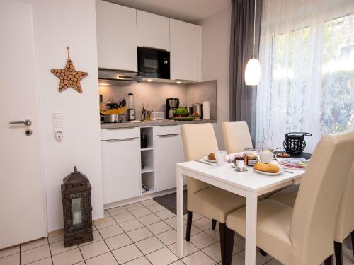 uma cozinha com uma mesa branca e cadeiras numa cozinha em Apartment Muschelweg-2 by Interhome em Norddeich