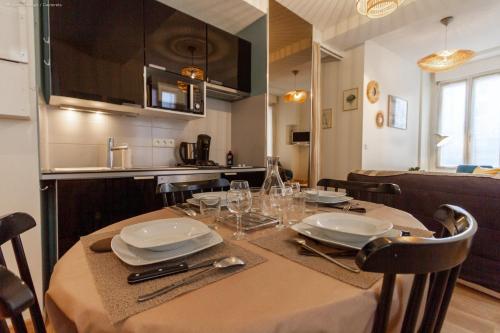 une table de salle à manger avec des assiettes et des verres dessus dans l'établissement Appartement cosy au cœur de la ville, au calme avec Wifi et linge de maison inclus, à Cauterets