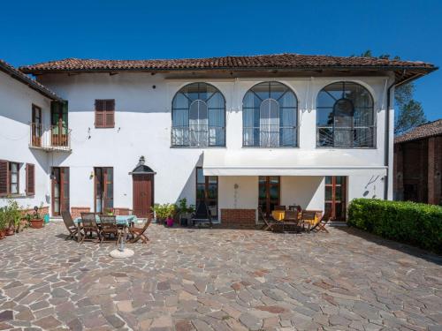 a large white house with a patio with tables and chairs at Apartment Paolo by Interhome in Azzano d'Asti