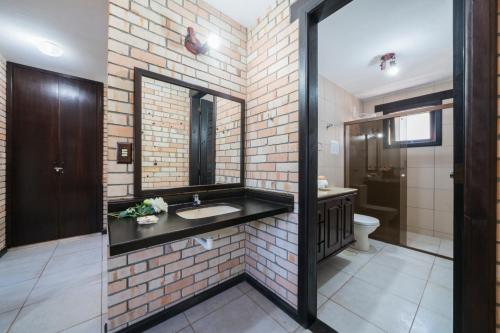 a bathroom with a sink and a brick wall at Pousada Albacora in Bombinhas