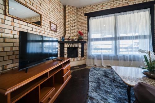 a living room with a television and a brick wall at Pousada Albacora in Bombinhas