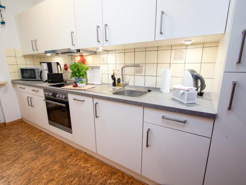eine Küche mit weißen Schränken und einer Spüle in der Unterkunft Apartment Tunnelstrasse-1 by Interhome in Norddeich